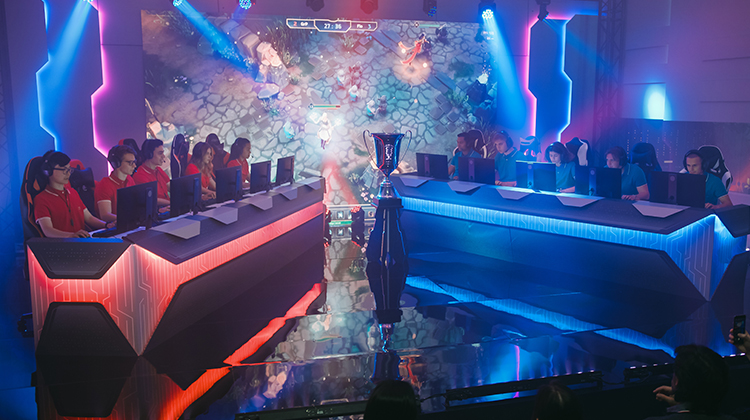 Woman speaks at conference in front of a crowd 
A crowd watches the stage of an esports tournament 
 